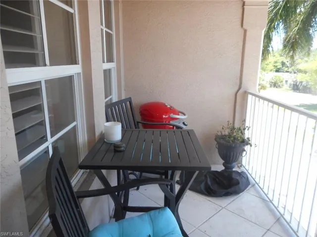 a backyard of a house with table and chairs floor to ceiling window and potted plants