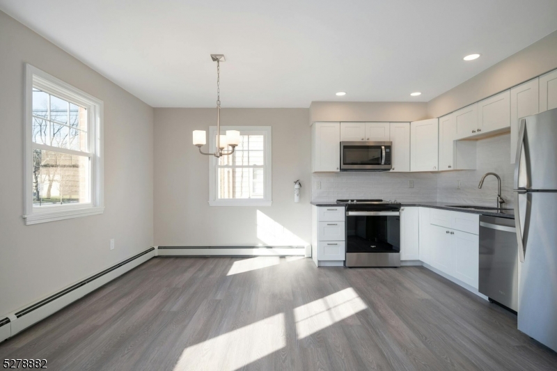 80 East Main Street, Unit 5 Mendham, NJ 07945 - Photo 10 of 28 a kitchen with granite countertop a stove top oven a sink dishwasher a refrigerator and a microwave oven with wooden floor