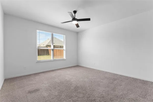 an empty room with windows and ceiling fan