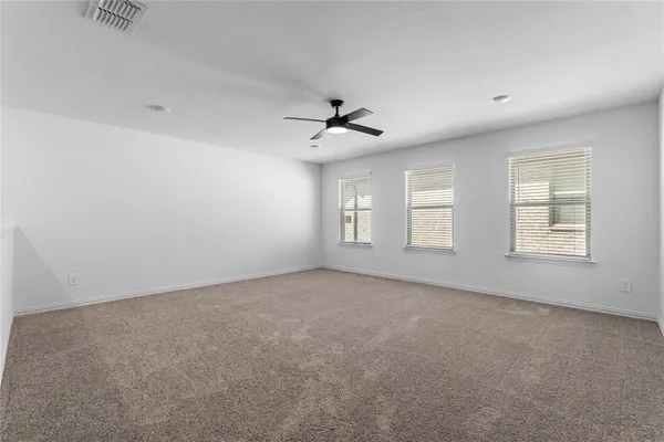 an empty room with windows and ceiling fan