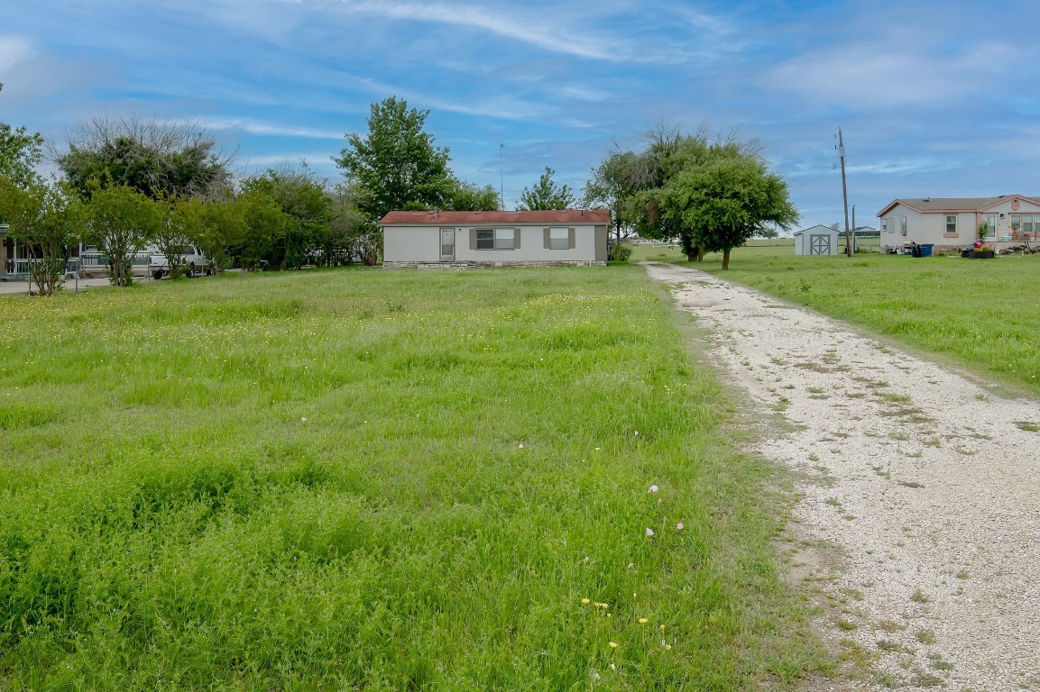 a view of a white house with a big yard and large trees