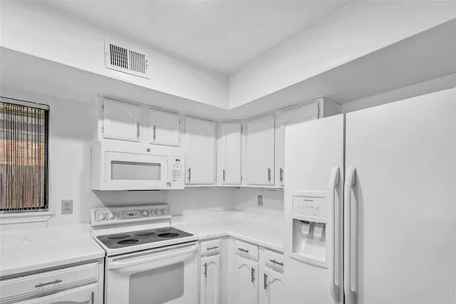 a kitchen with white cabinets and white appliances