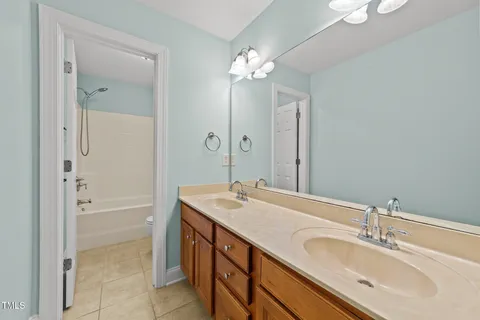 a bathroom with a sink double vanity granite tub shower and a mirror