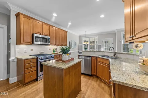 a kitchen with stainless steel appliances granite countertop wooden cabinets a stove top oven a sink and dishwasher