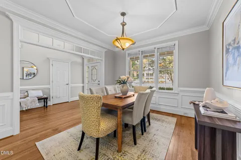 a dining room with wooden floor a chandelier a wooden table and chairs