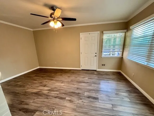 a view of an empty room with wooden floor and a window