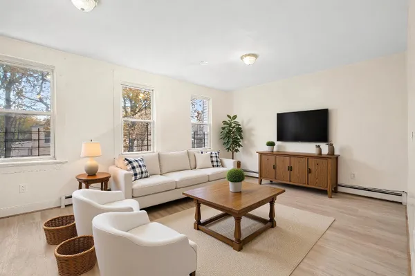 a living room with furniture a flat screen tv and a window