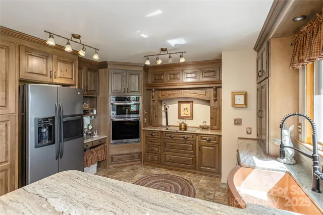 a kitchen with stainless steel appliances kitchen island granite countertop a refrigerator and a sink