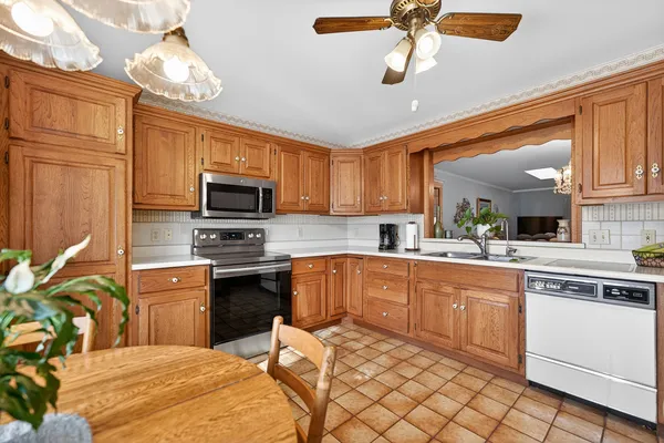 a kitchen with stainless steel appliances granite countertop a sink dishwasher a stove top oven a refrigerator with island and chairs