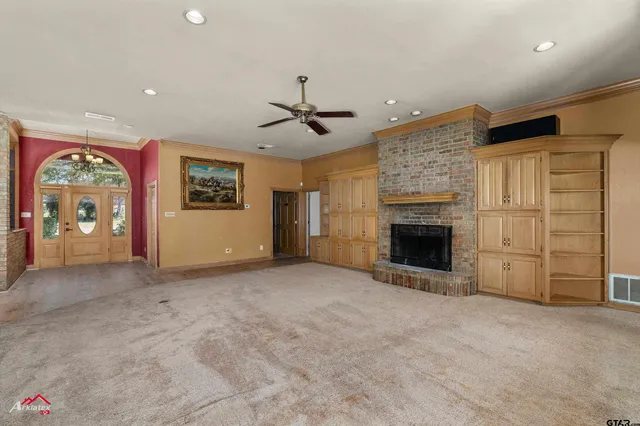 a view of an empty room with a fireplace and a ceiling fan