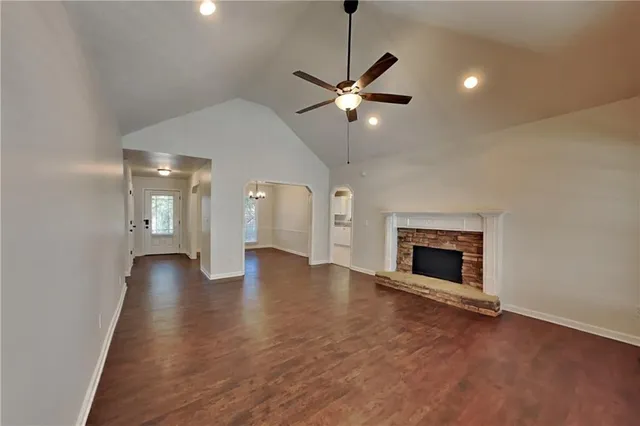 a view of an empty room with wooden floor fireplace and a window