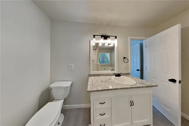 a bathroom with a granite countertop sink toilet and mirror