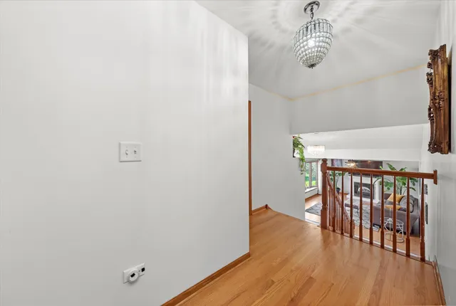 a view of a hallway with wooden floor and chandelier