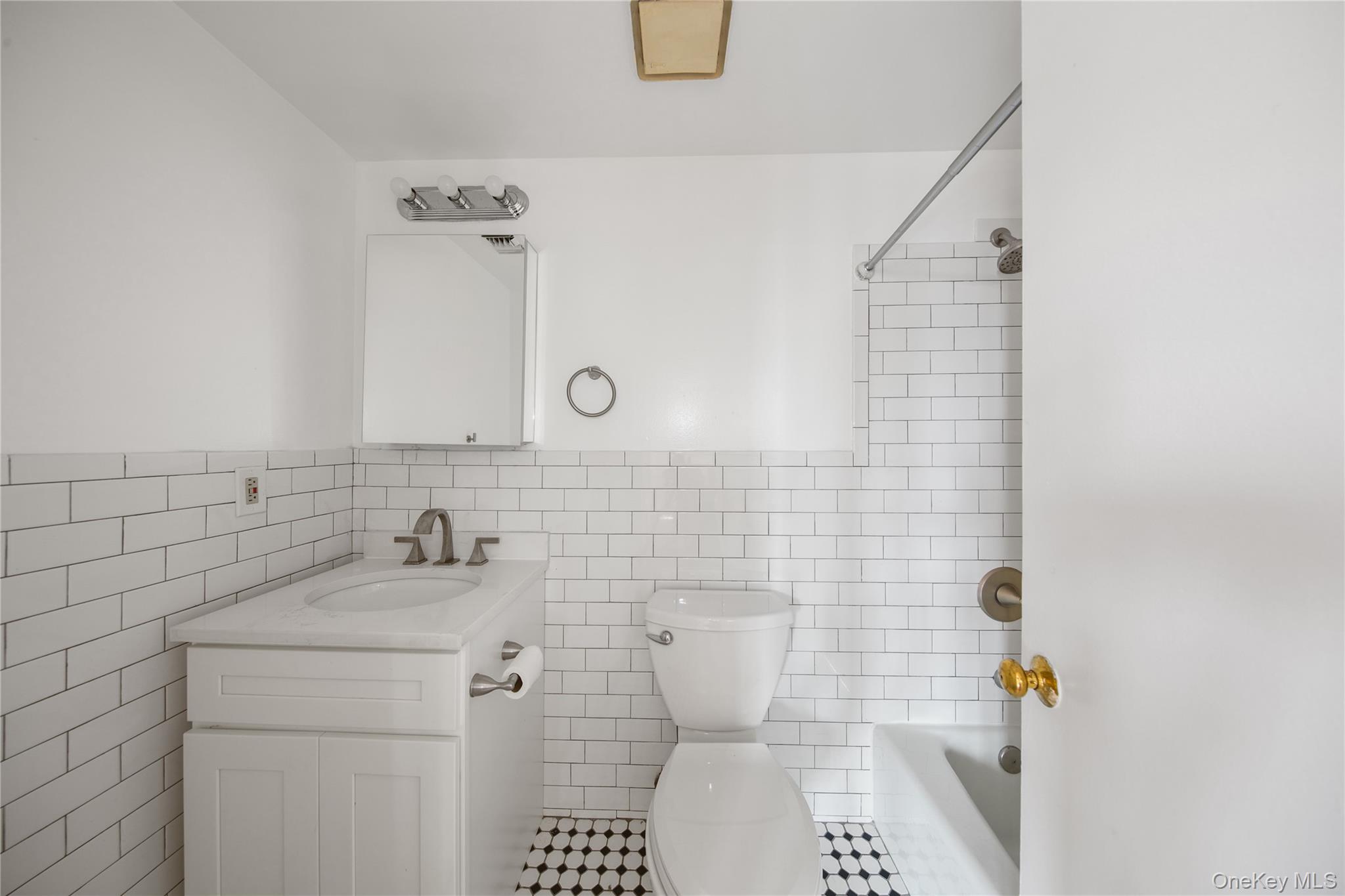 207 Chateau Rive, Unit 207 Peekskill, NY 10566 - Photo 13 of 16 Full bath featuring bathing tub / shower combination, vanity, tile walls, and a wainscoted wall