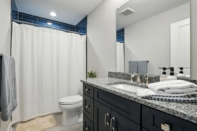 a bathroom with a granite countertop sink toilet and a mirror