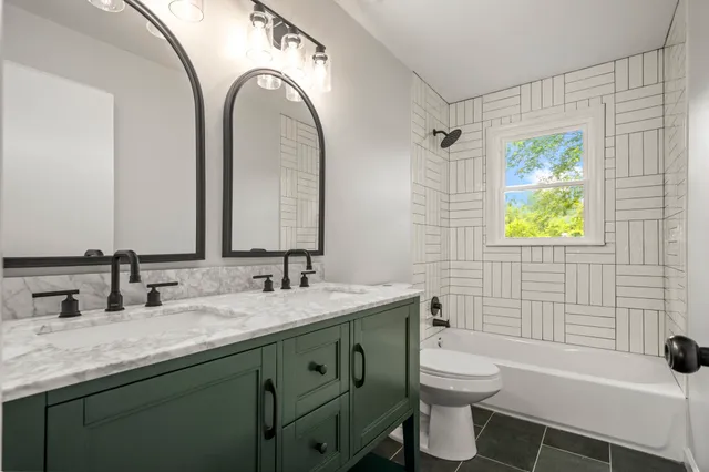 a bathroom with a granite countertop toilet sink and mirror