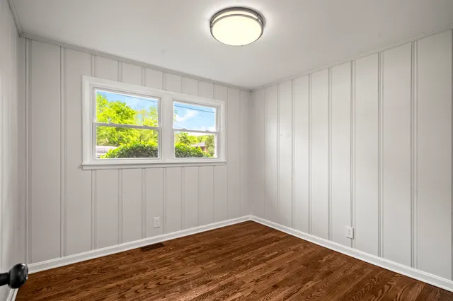 a view of an empty room with window and wooden floor