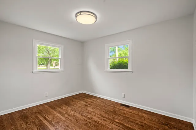 an empty room with window and wooden floor