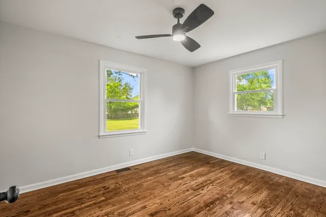 a view of empty room with wooden floor and window