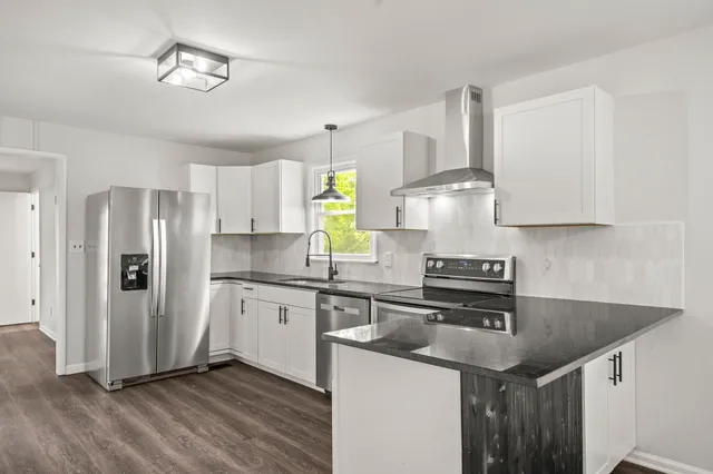 a kitchen with stainless steel appliances granite countertop a sink a stove and a refrigerator