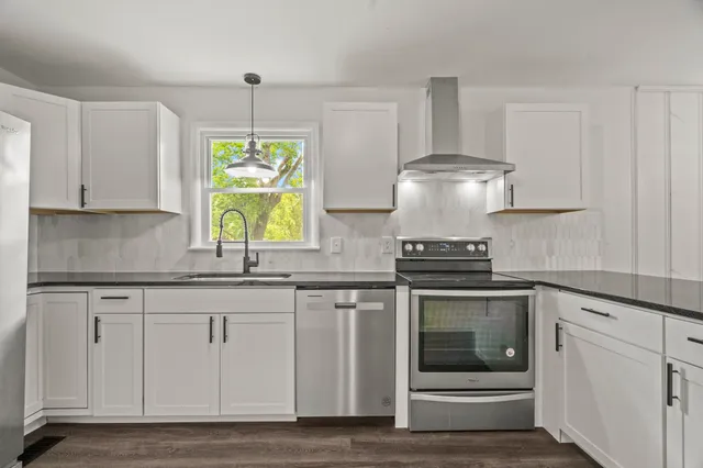 a kitchen with stainless steel appliances granite countertop a stove and a white cabinets
