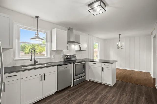 a kitchen with white cabinets appliances and a window