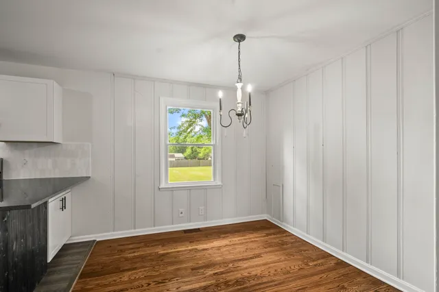 a view of an empty room with window and wooden floor
