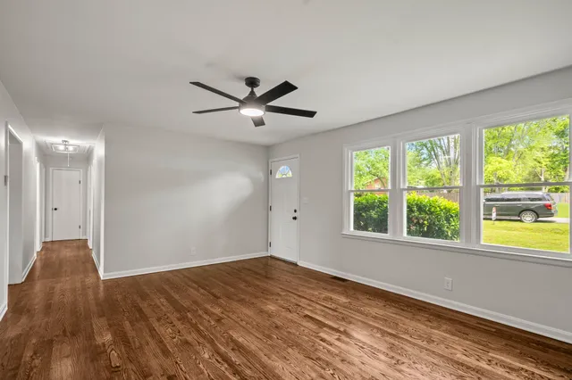 a view of an empty room with a window and wooden floor