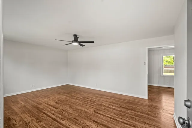 an empty room with wooden floor cabinet and windows