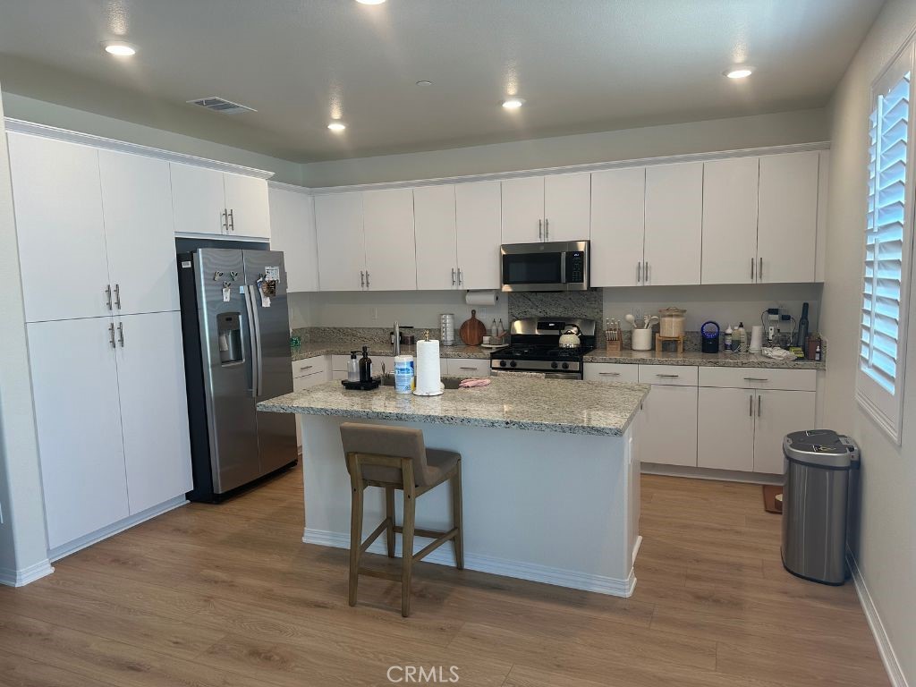 2511 Gunner Ridge Way Rialto, CA 92377 - Photo 15 of 37 a kitchen with stainless steel appliances granite countertop a refrigerator a sink a stove a microwave and wooden floor