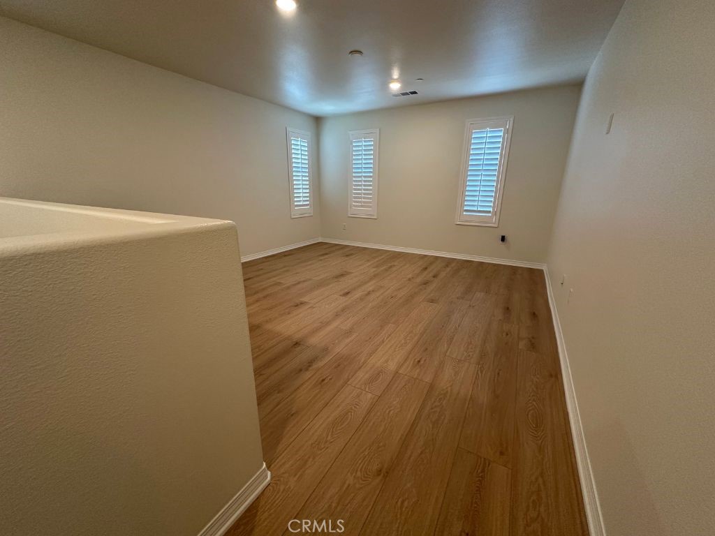 2511 Gunner Ridge Way Rialto, CA 92377 - Photo 17 of 37 an empty room with wooden floor and windows