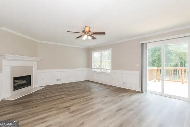 an empty room with wooden floor fireplace and windows