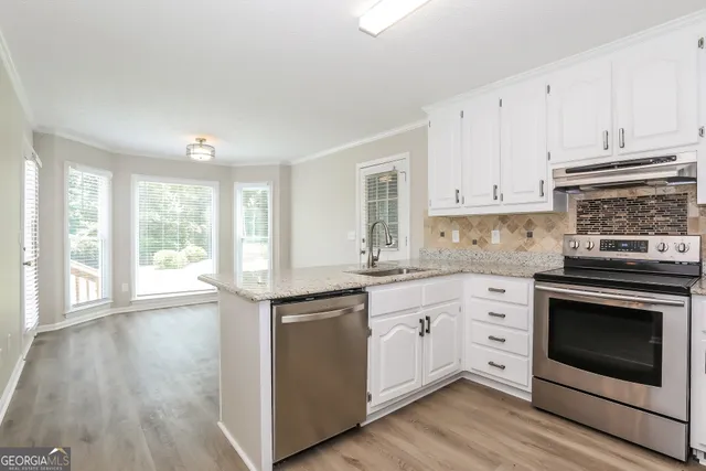 a kitchen with stainless steel appliances granite countertop a stove and white cabinets