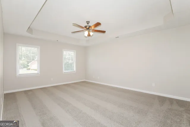 an empty room with windows and fan