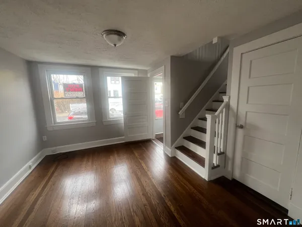 a view of an empty room with wooden floor and a window