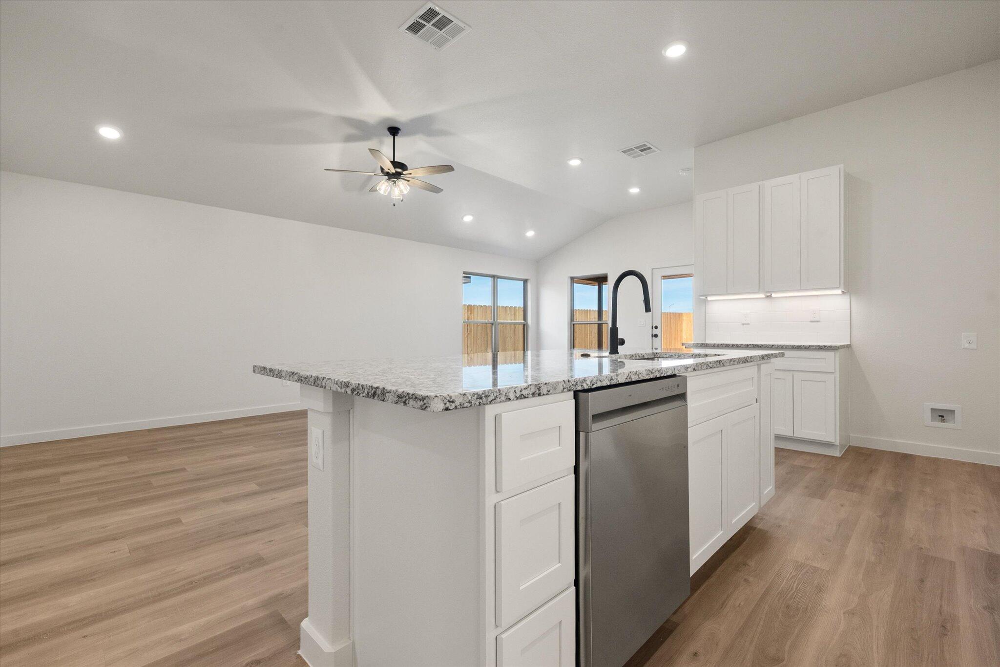 3114 138th Place Lubbock, TX 79423 - Photo 11 of 21 a kitchen with a refrigerator a sink and dishwasher with wooden floor