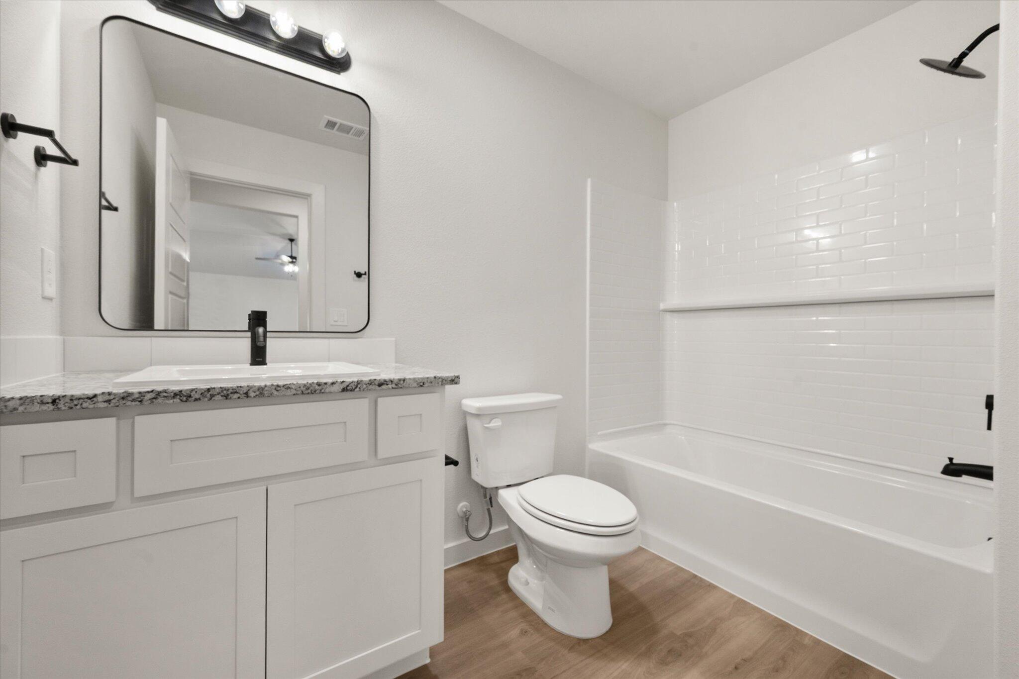 3114 138th Place Lubbock, TX 79423 - Photo 18 of 21 a bathroom with a granite countertop toilet sink and mirror