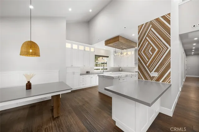 a large white kitchen with stainless steel appliances granite countertop a stove oven a sink dishwasher and white cabinets with wooden floor