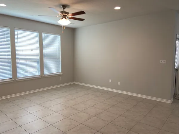 an empty room with windows and fan