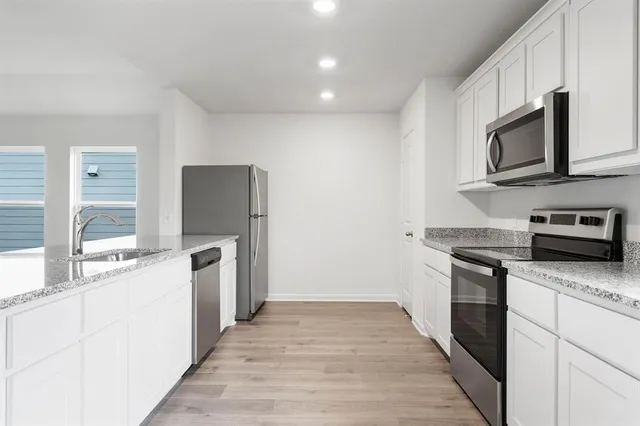 a kitchen with stainless steel appliances granite countertop a stove a sink and a microwave