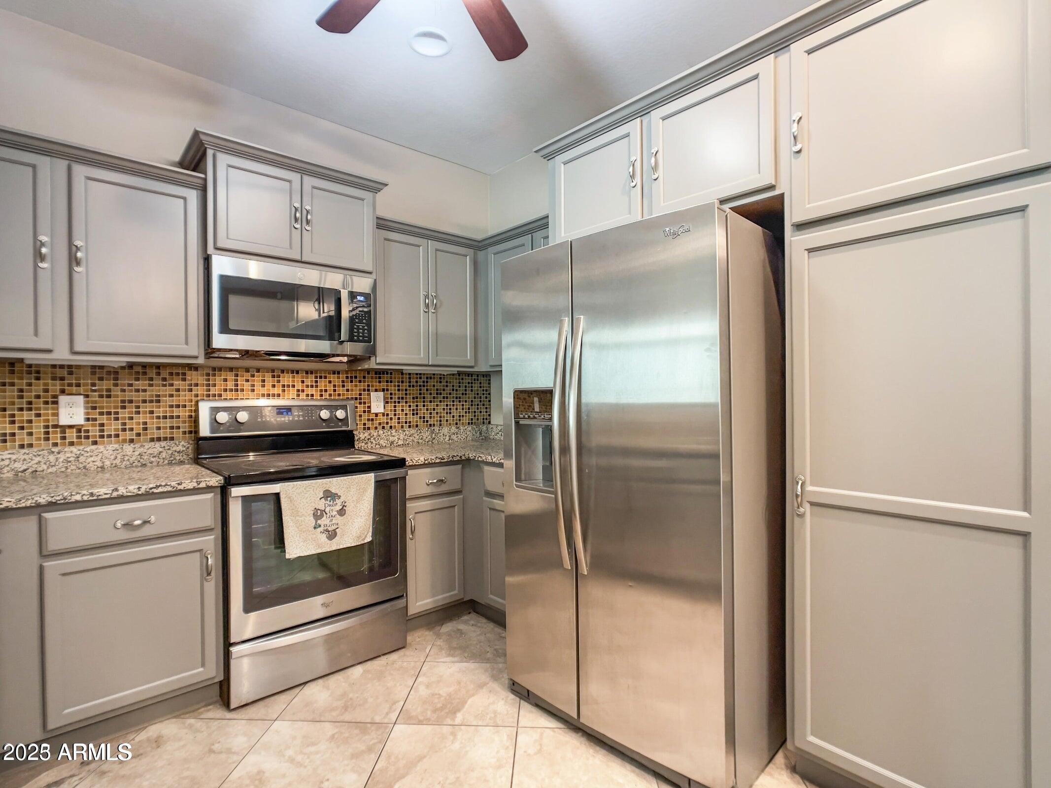 1958 West Busoni Place Phoenix, AZ 85023 - Photo 25 of 42 a kitchen with stainless steel appliances granite countertop a refrigerator and a stove top oven