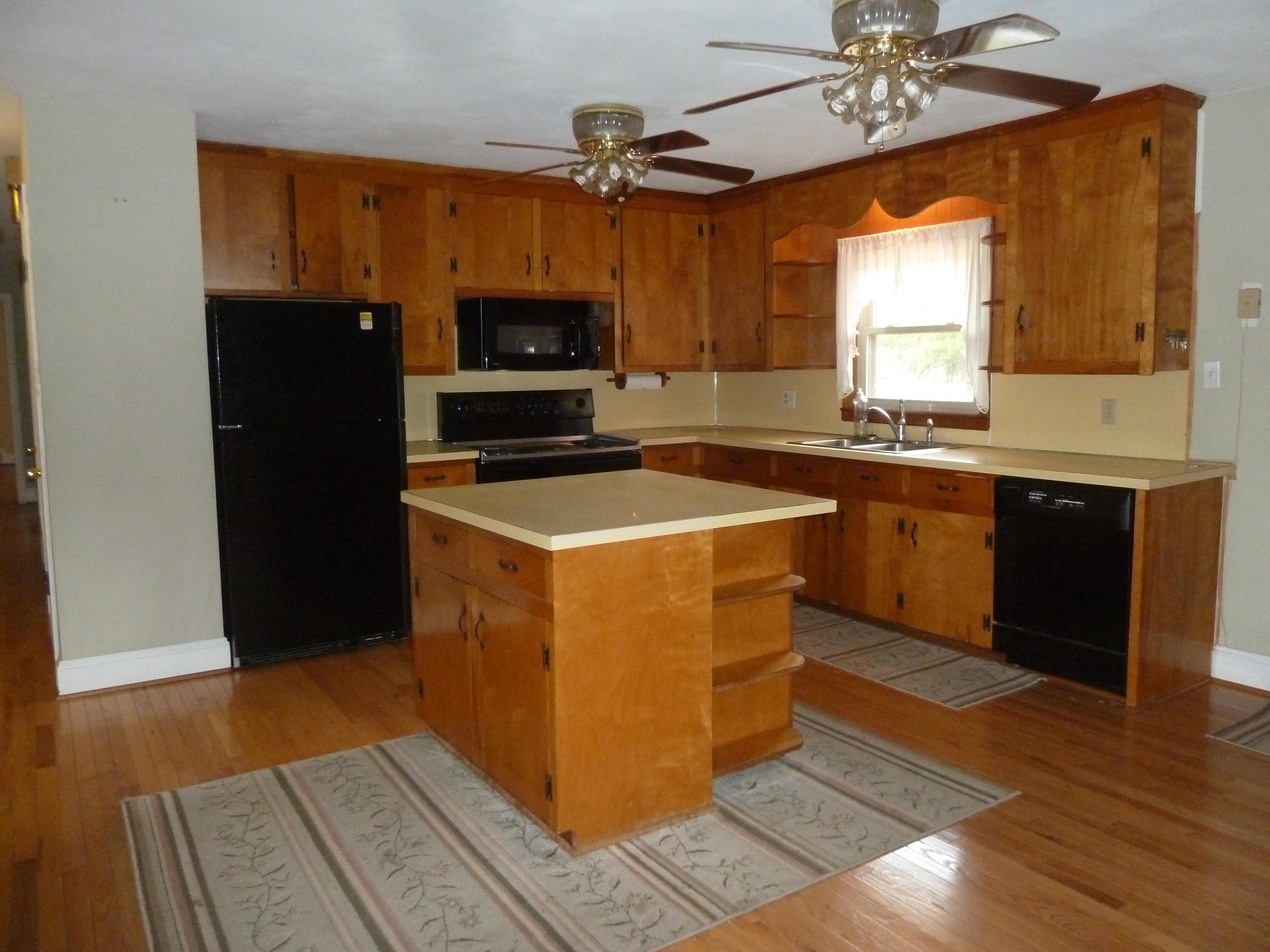 13692 West Gretna Road Sandy Level, VA 24161 - Photo 8 of 58 a kitchen with stainless steel appliances a stove a refrigerator a sink a microwave oven and a dining table with wooden floor