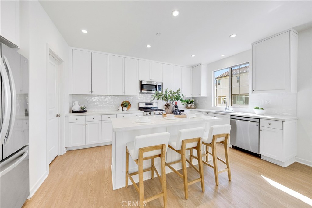 716 Spring Garden Irvine, CA 92618 - Photo 7 of 44 a kitchen with white cabinets and stainless steel appliances