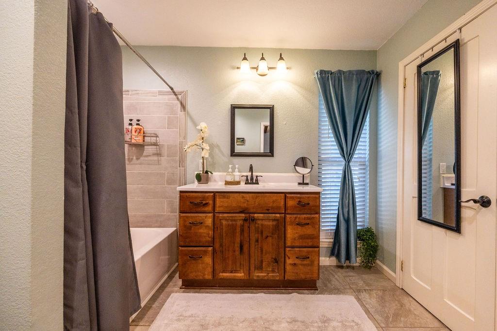 384 Ft Graham Road Waco, TX 76705 - Photo 15 of 36 Wood-finish vanity with white countertop, chrome faucet, and rectangular mirror