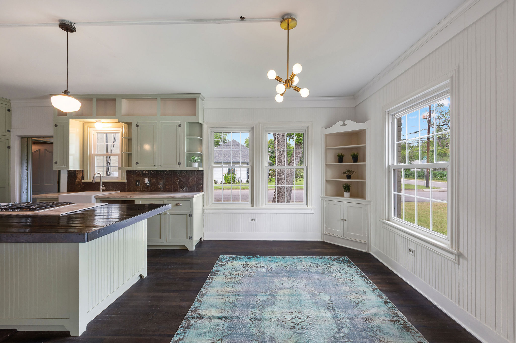 948 Maple Street Lockhart, TX 78644 - Photo 10 of 40 A luminous kitchen featuring an island, gas cooktop, and built-in shelving, all set against rich dark wood flooring.