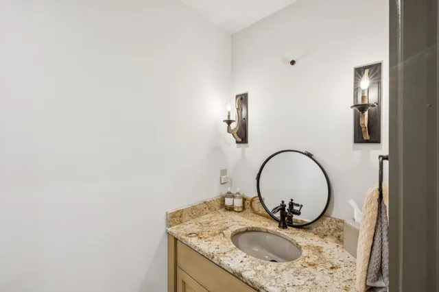 a bathroom with a granite countertop sink a toilet a mirror and shower