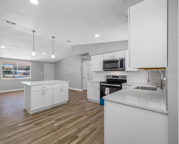 a kitchen with a sink stainless steel appliances and white cabinets