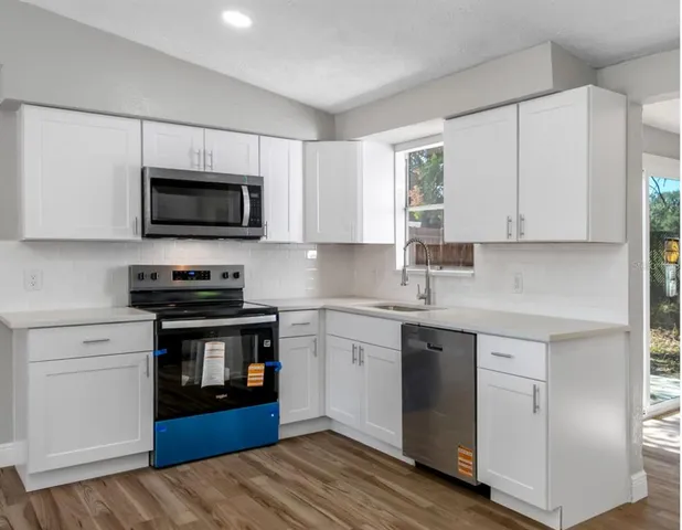 a kitchen with cabinets stainless steel appliances and a window