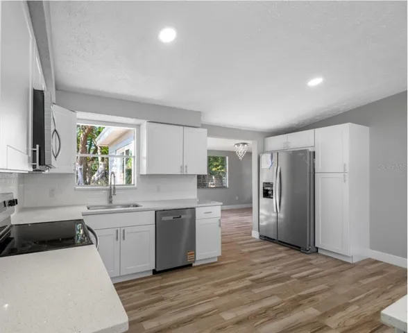 a kitchen with stainless steel appliances a sink a stove a refrigerator and cabinets