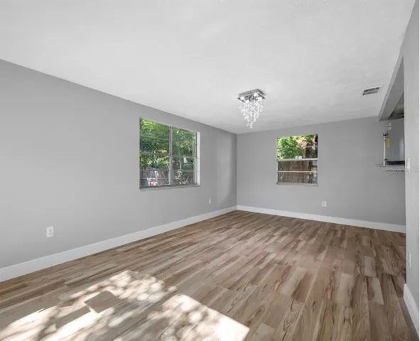 a view of empty room with wooden floor and fan